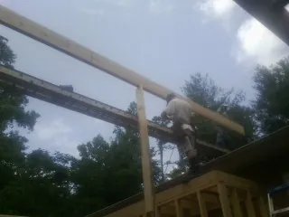 Carpenter setting a ridge beam over a new addition frame — Ice Dam Removal by Roofing Brothers in Laurens