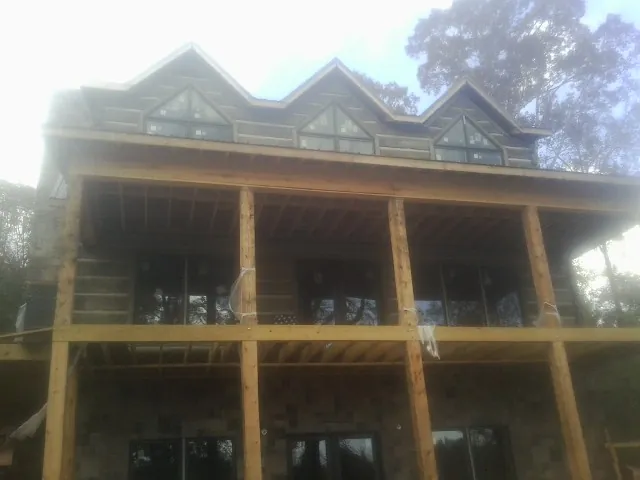 Dormers and porch framing on a large log home under construction — Roof Coating work by our crew in Laurens