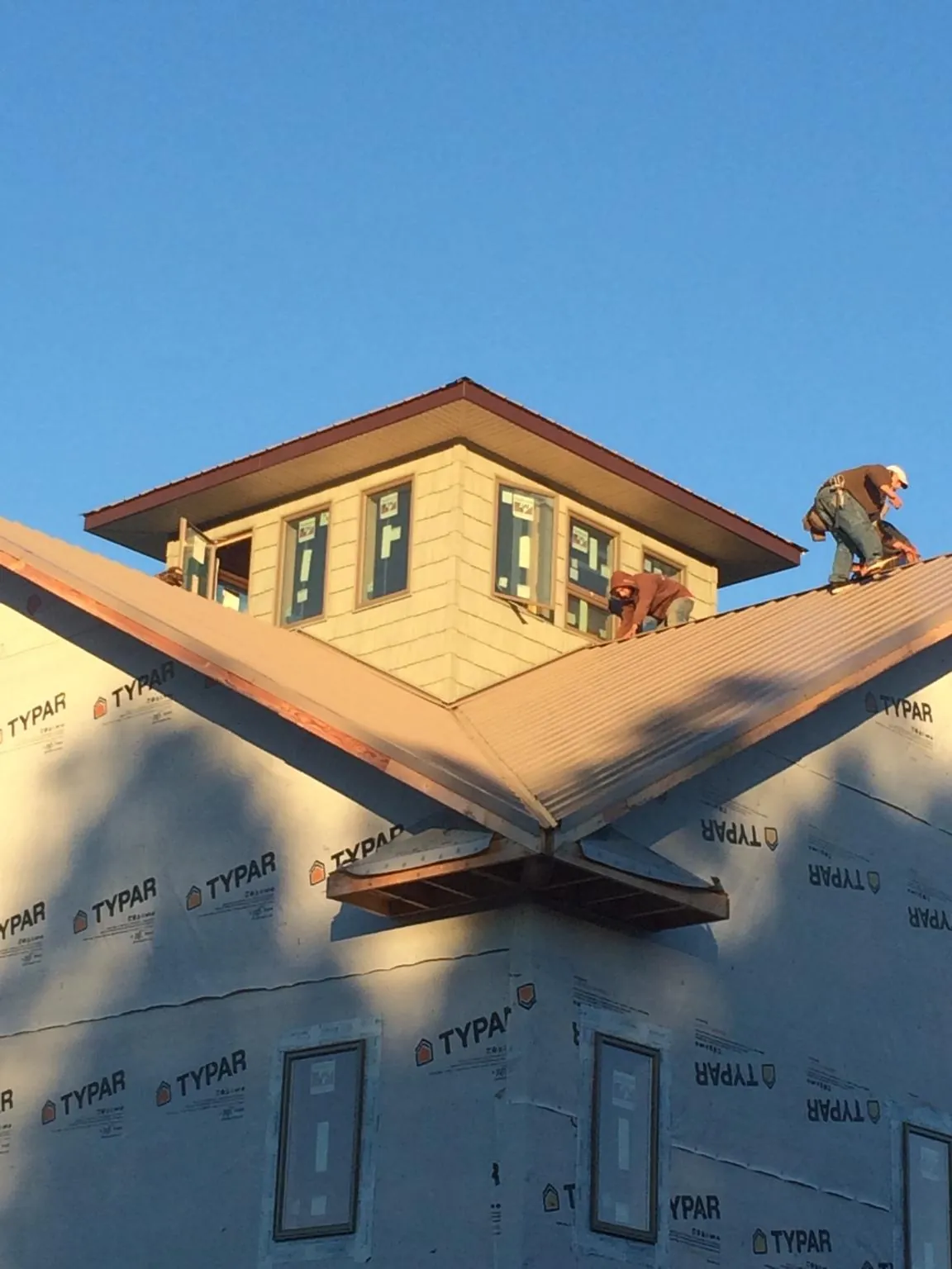 Roofers working around a rooftop cupola on a new metal roof at sunset — Roof Waterproofing in Laurens by Roofing Brothers